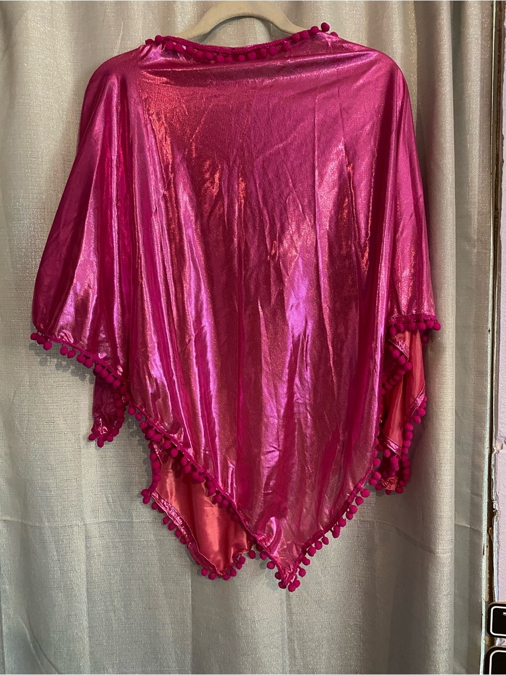 1980’s vibe , pink, metallic-finish poncho or cover-up featuring a pom-pom trim